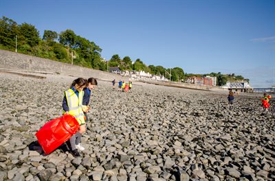 Plant yn gwisgo siacedi golygfa uchel yn casglu sbwriel ar draeth Penarth